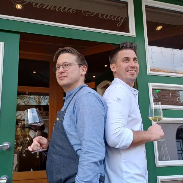 Markus und Thomas Haag mit einem Weinglas in der Hand vor ihrem Wirtshaus.  