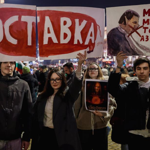 Junge Protestierende halten bei einer Demo am 10. Dezember ein Plakat mit einem Schwein hoch, auf dem „Rücktritt“ steht.  