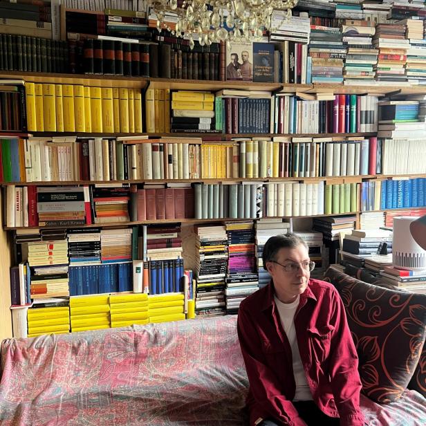 Franco Schedl sitzt vor seinen Büchern