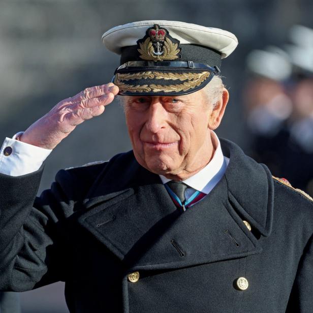 König Charles III. in Marineuniform salutiert.