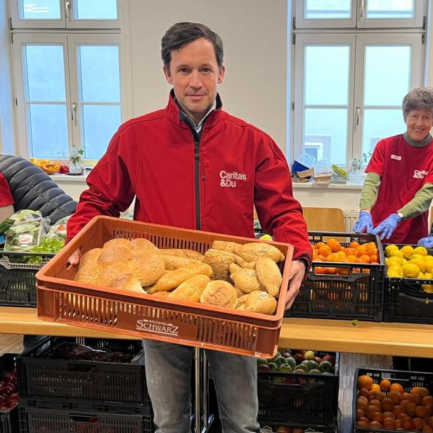 Klaus Schwertner hält bei der Lebensmittelausgabe eine Box mit Broten.