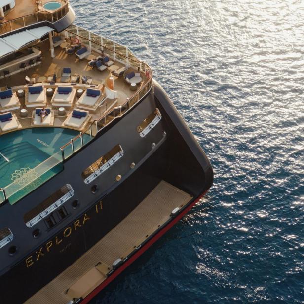 Vogelperspektive auf ein Reiseschiffes mit Pool auf dem Deck und Sonnenliegen