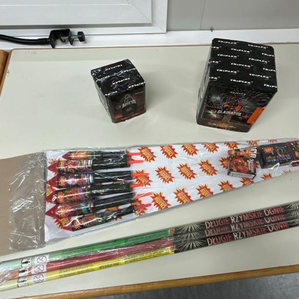 Mehrere Feuerwerkskörper, darunter Raketen, Batterien und römische Lichter, liegen auf einem Tisch.