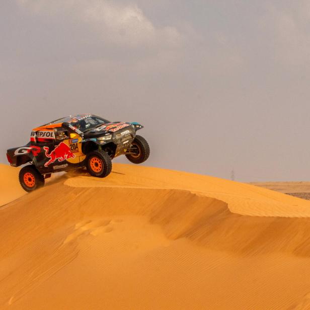 Ein Auto fährt bei der Rallye Dakar über eine Sanddüne.