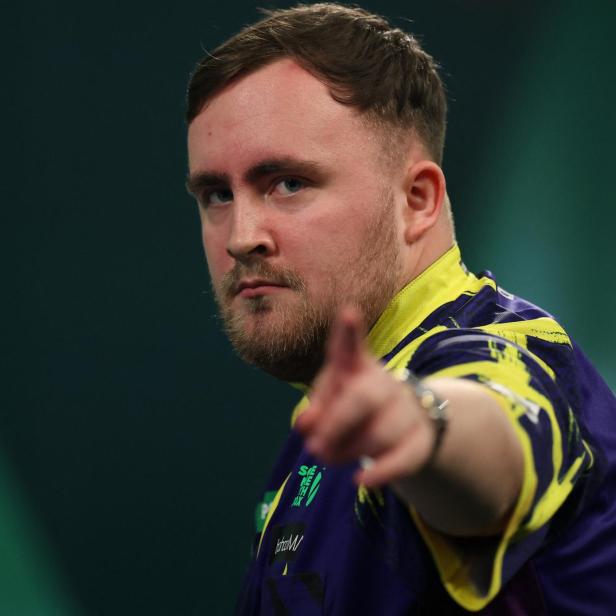 Luke Littler zeigt mit dem Finger nach vorne.