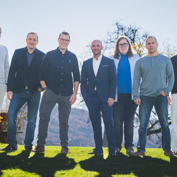 Mehrere Personen stehen auf einer grünen Wiese und blicken in die Kamera