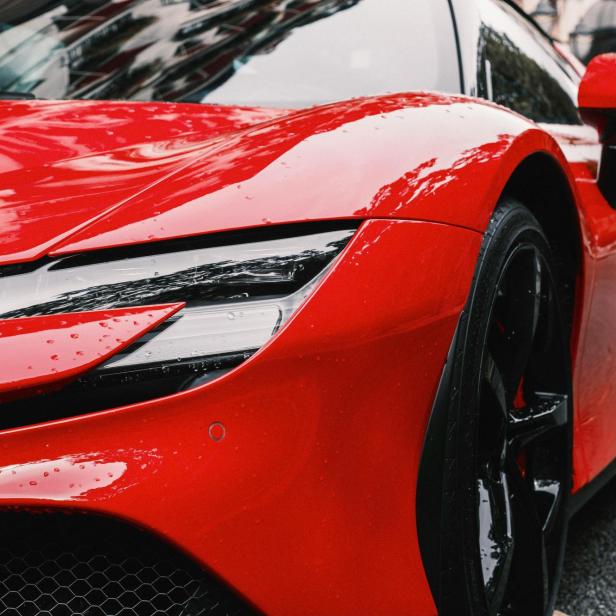 Roter Sportwagen mit glänzendem Lack und Wassertropfen auf der Motorhaube.
