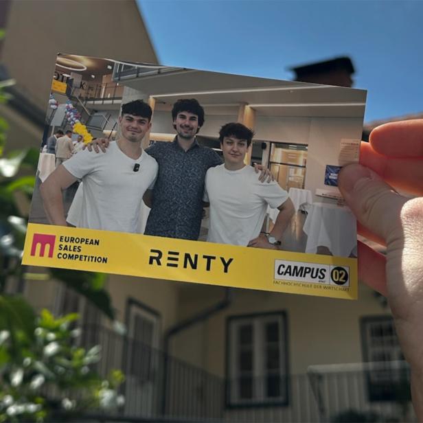 Eine Hand hält eine Karte auf der Werbung für "Renty" gemacht wird. Im Hintergrund sieht man die Außenansicht eines Hauses.
