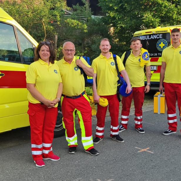 Mehrere Rettungssanitäter stehen vor einem Rettungswagen.