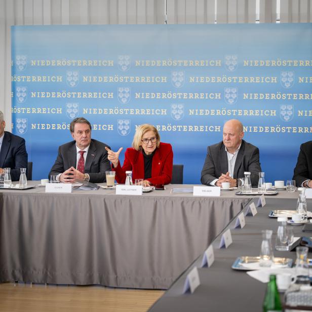 Eine Gruppe von Personen, darunter Mikl-Leitner, sitzt an einem Tisch vor einem Hintergrund mit dem Schriftzug "Niederösterreich".