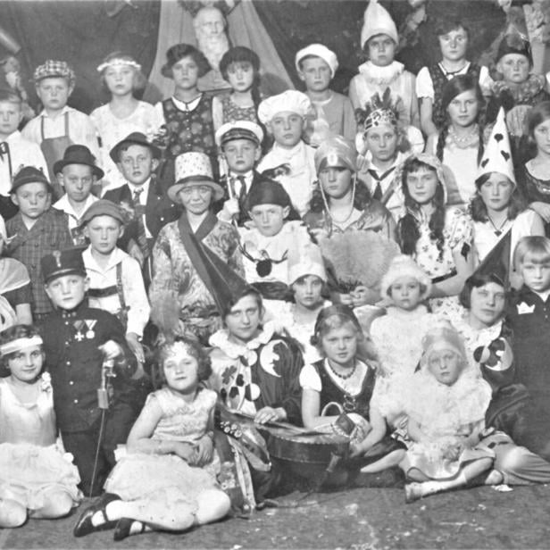 Viele Kinder in fantasievollen Kostümen sitzen und stehen in mehreren Reihen für ein Gruppenporträt zusammen.