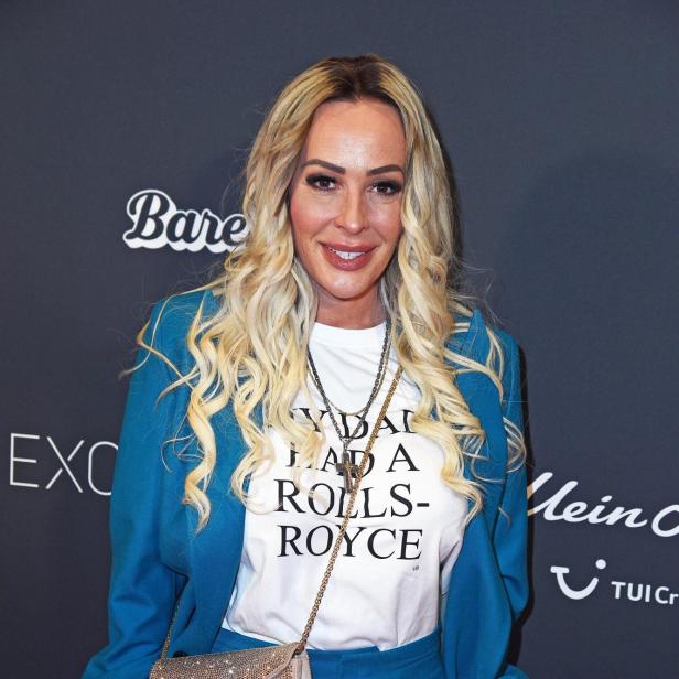 Cora Schumacher mit weißem T-Shirt und blauen Anzug auf einem Event