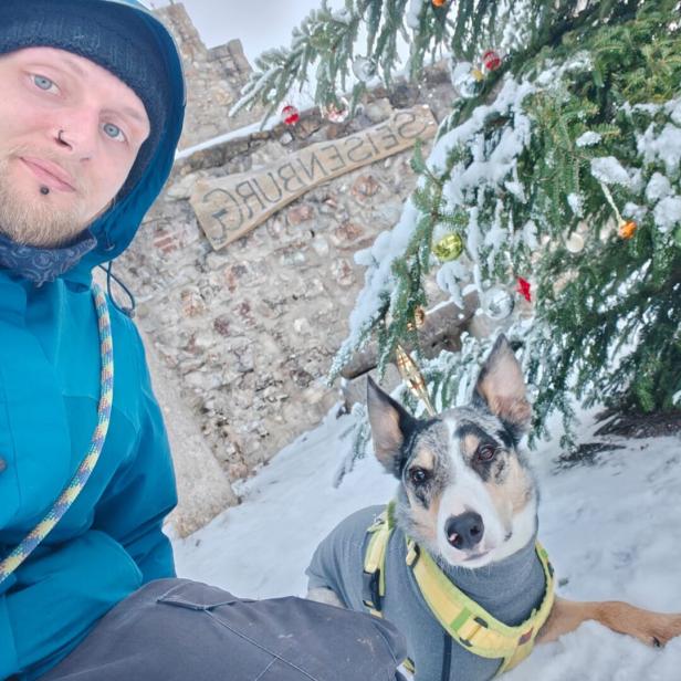 Ein Mann mit einem Hund schaut in die Kamera