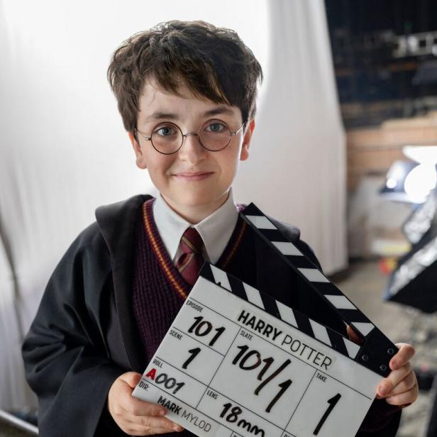 Ein junger Schauspieler im Harry-Potter-Kostüm hält eine Filmklappe mit der Aufschrift "Harry Potter, Episode 101".