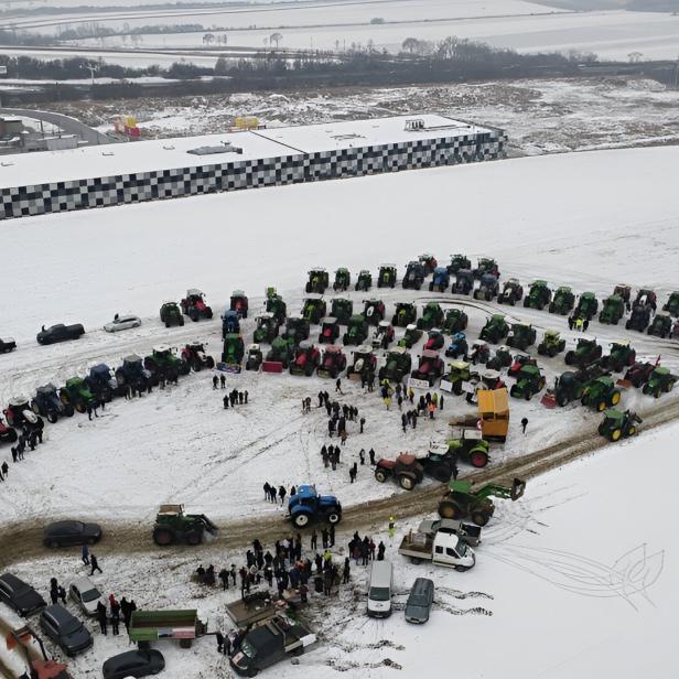 Viele Traktoren und Menschen versammeln sich auf einem verschneiten Feld in einer großen Kreisformation.