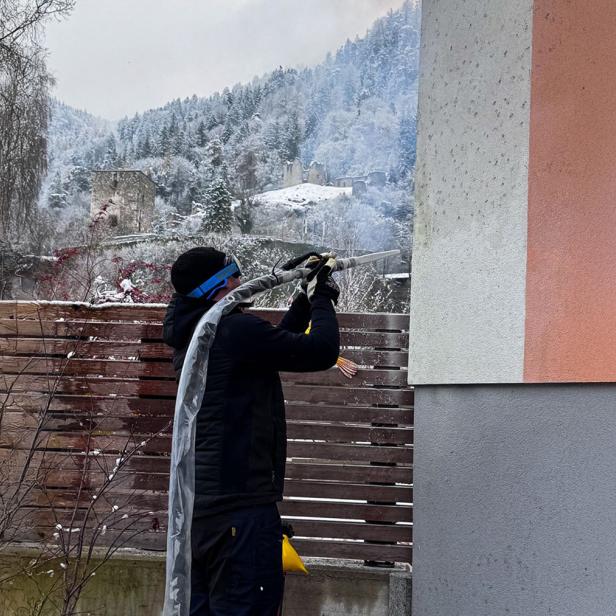 Person reinigt eine Hausfassade im Winter mit einem Trockeneisstrahlgerät.