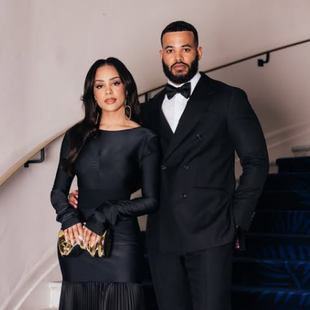 Kristy Sarah und Desmond Scott posieren elegant gekleidet gemeinsam auf einer Treppe.