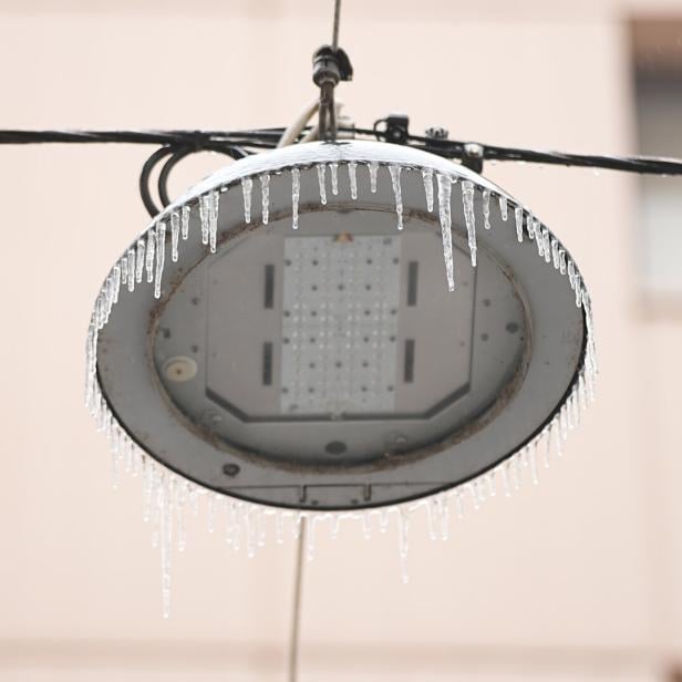 An einer Straßenlaterne hängen zahlreiche Eiszapfen herab.