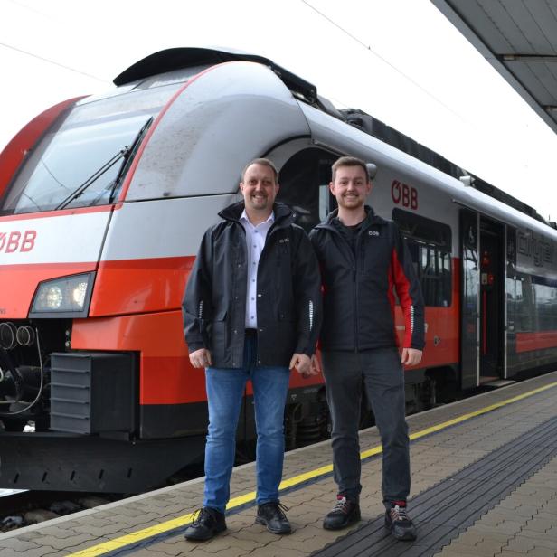 Zwei Männer stehen vor einem rot-weißen ÖBB Cityjet-Zug auf einem Bahnsteig.