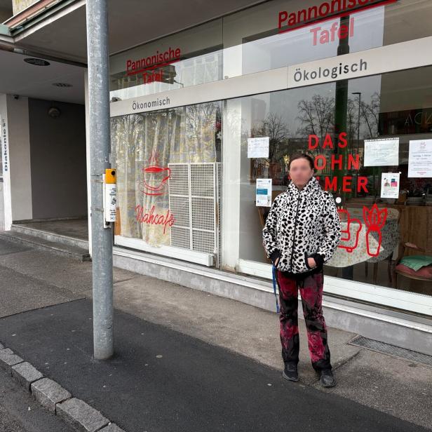 Eine Person steht vor einem Schaufenster mit der Aufschrift „Pannonische Tafel“ und bunten Bildern an der Scheibe.