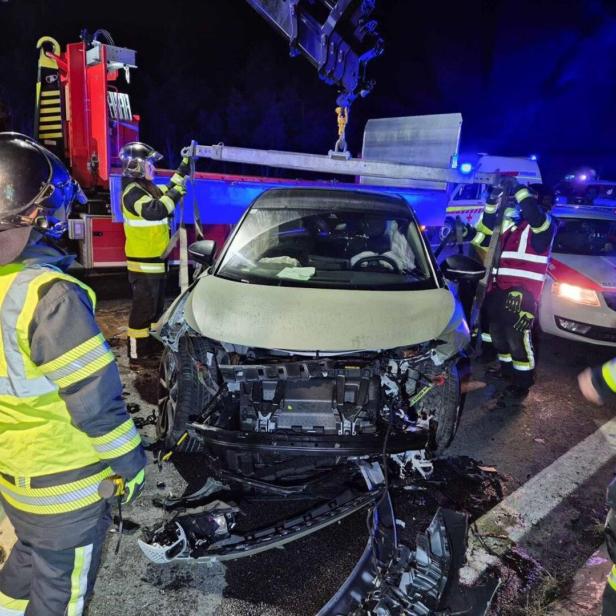 Mehrere Einsatzkräfte vor einem Unfallfahrzeug mit Totalschaden.