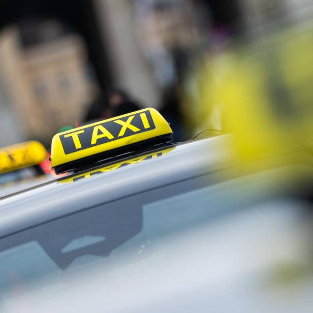 Mehrere Taxis mit gelben Leuchtschildern stehen hintereinander auf einer Straße.