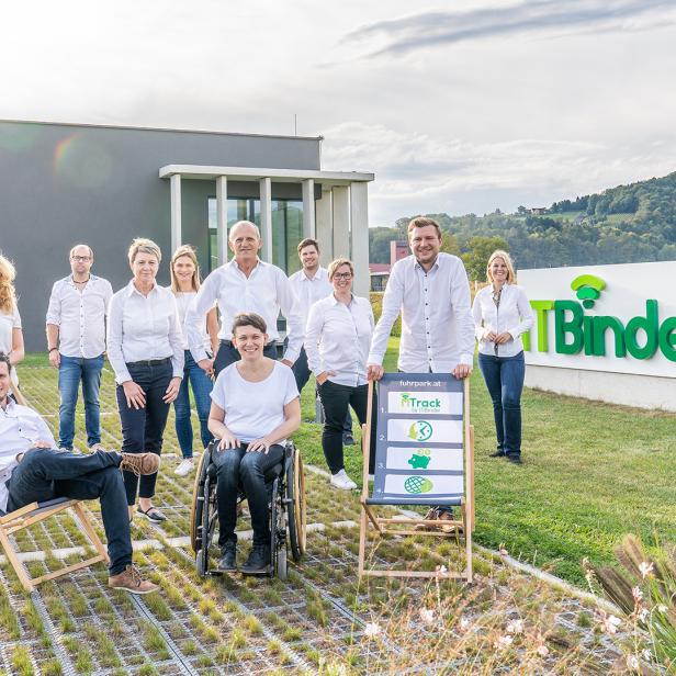Gruppe von Mitarbeitenden vor dem ITBinder-Gebäude und einem großen Firmenschild im Grünen.