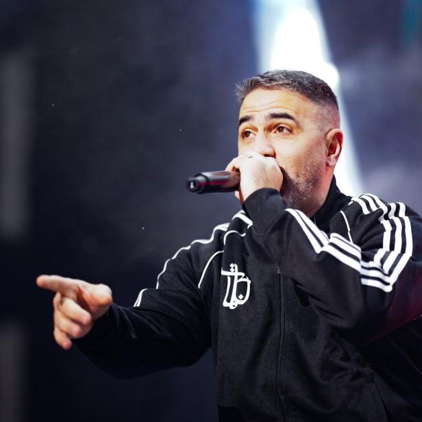 Bushido in Trainingsjacke performt mit Mikrofon und zeigt mit dem Finger.