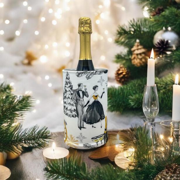 Sektflasche im festlich dekorierten Weinkühler, umgeben von Kerzen und Tannenzweigen.