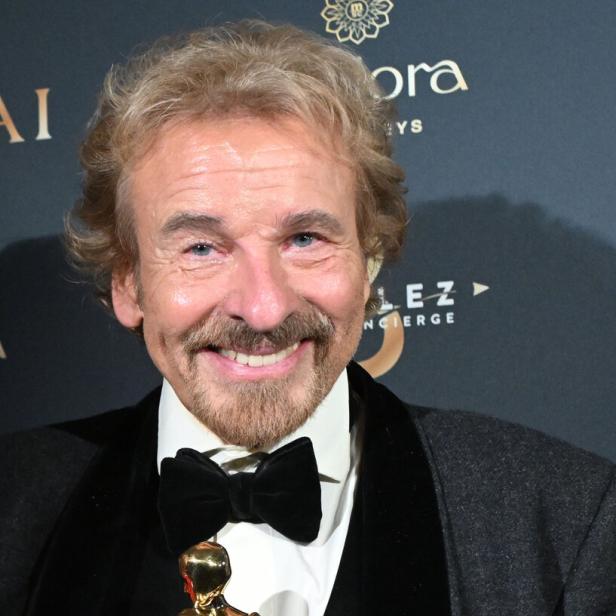Thomas Gottschalk lächelt mit Fliege und einer goldenen Statue in der Hand.
