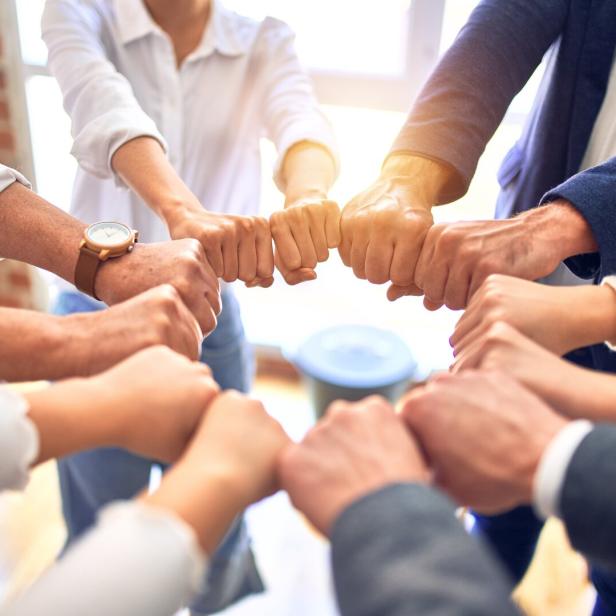Group of business workers standing bumping fists at the office
