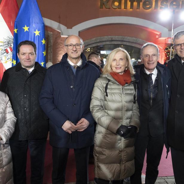 Sechs Menschen tragen Jacken und stehen vor beleuchtetem Gebäude