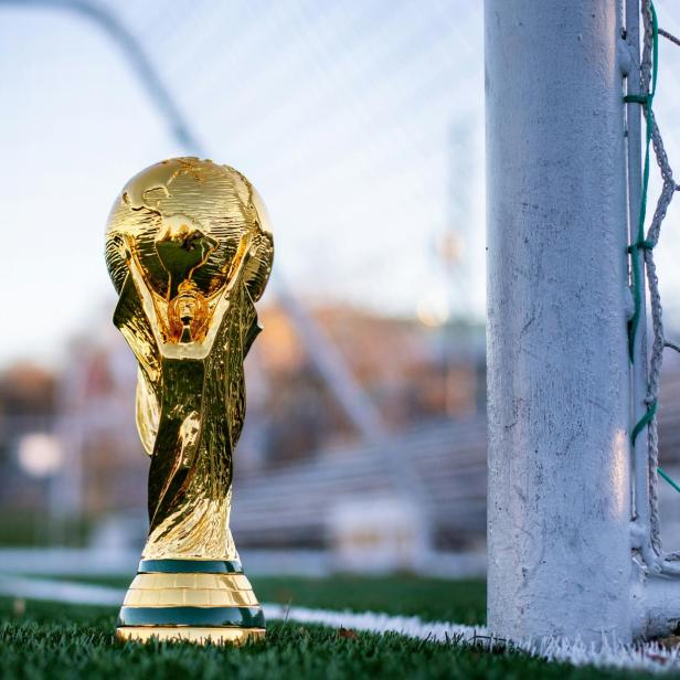 Der WM-Pokal steht auf dem Rasen direkt neben einem Fußballtor.