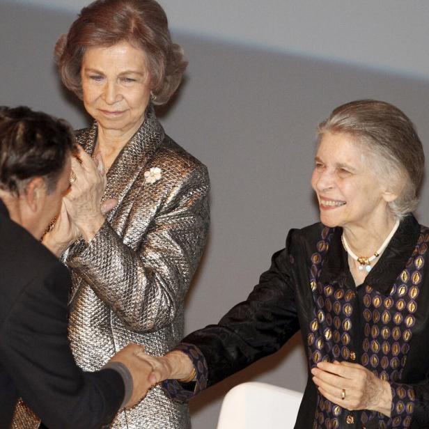 Prinzessin Irene lächelt und schüttelt einem Mann die Hand, während Altkönigin Sofía daneben steht und zuschaut.