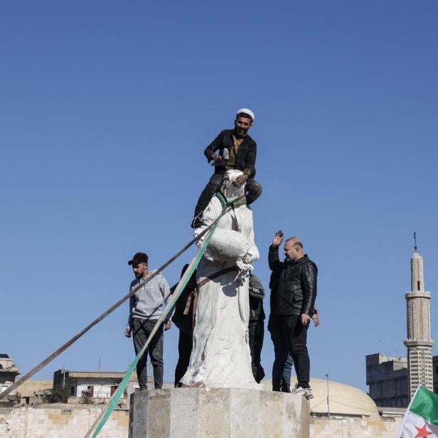 Araber  feiern die Vorstöße: Im Bild stürzen sie eine Statue der  kurdischen Frauenmiliz in ar-Raqqa.