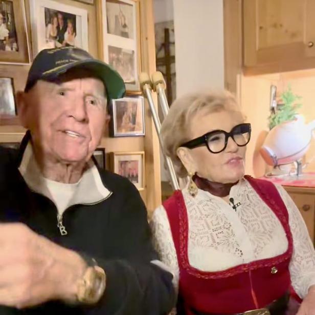 Prinz Frédéric von Anhalt sitzt mit Rosi Schipflinger auf einer Bank, im Hintergrund sind Krücken zu sehen.