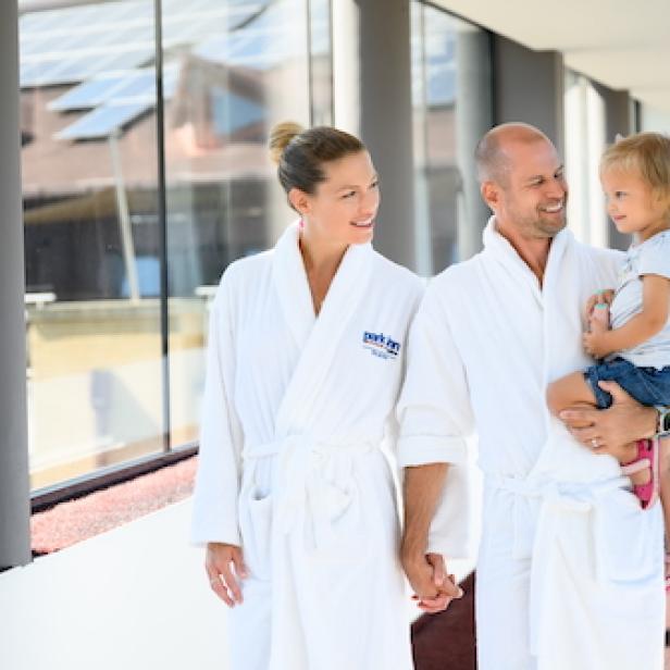 Eine Familie geht in Bademänteln durch ein Hotel 