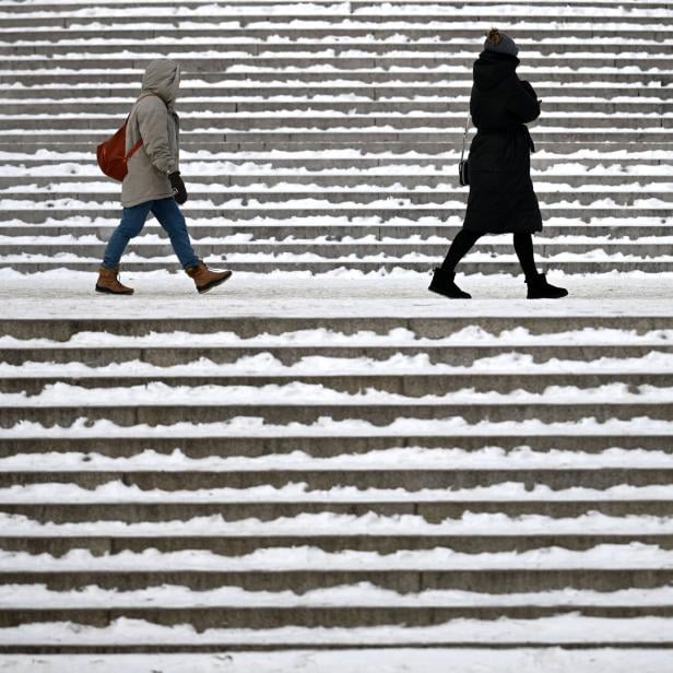 Zwei Personen gehen auf einer schneebedeckten Treppe entlang.