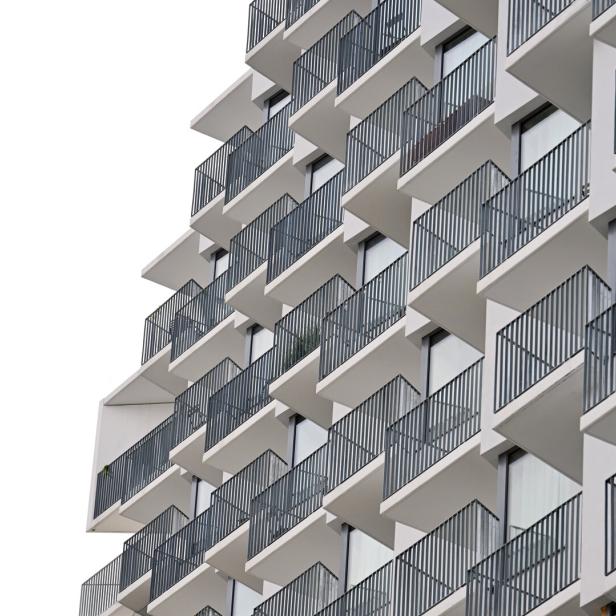 Mehrstöckiges Gebäude mit vielen modernen, versetzt angeordneten Balkonen und Glasfronten.