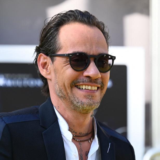 Marc Anthony lächelt mit Sonnenbrille und Anzug.
