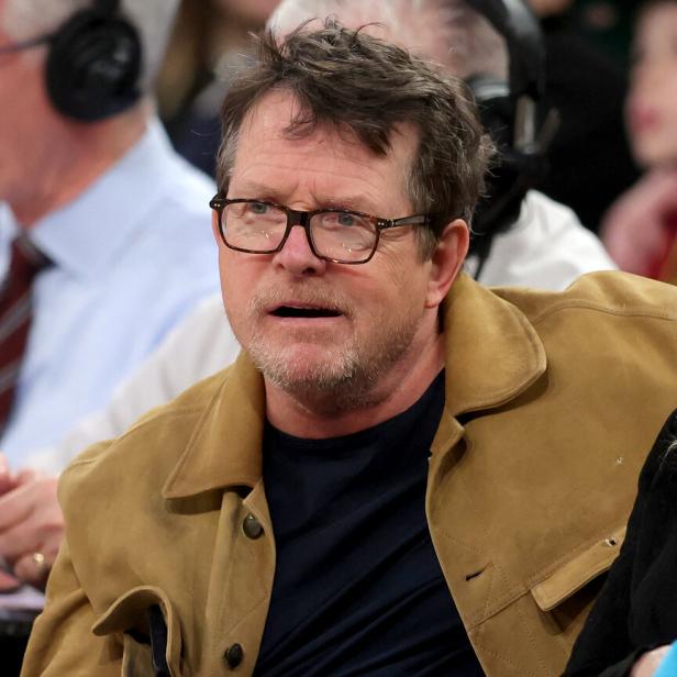 Michael J. Fox sitzt mit Brille und brauner Jacke im Publikum.