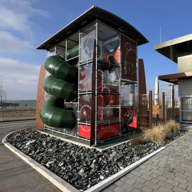 Ein moderner McDonald's mit einem großen, überdachten Kletter- und Rutschspielplatz im Außenbereich.