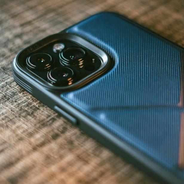 Smartphone mit blauer Schutzhülle liegt auf einer Holzoberfläche.