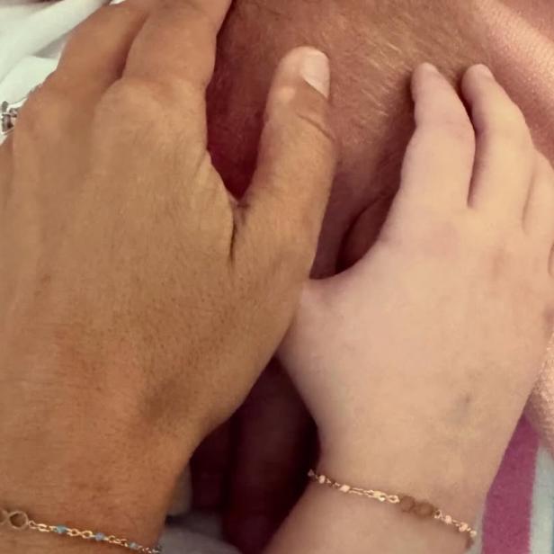 Drei Hände mit identischen Armbändern halten sich auf einer Decke.