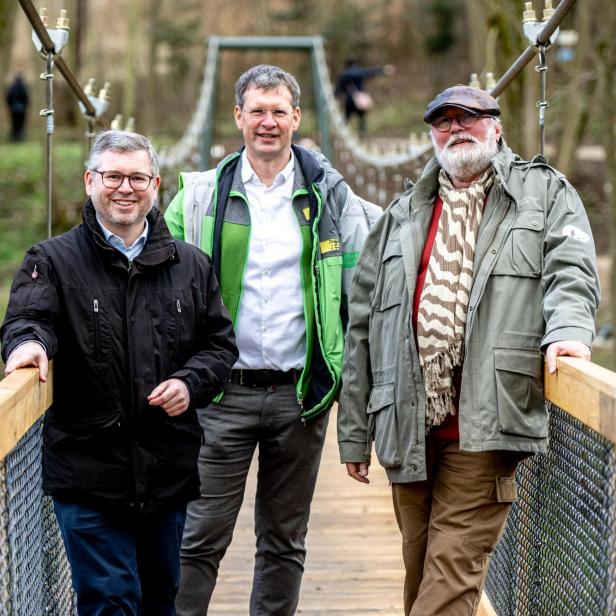 Drei Männer stehen auf einer Hängebrücke