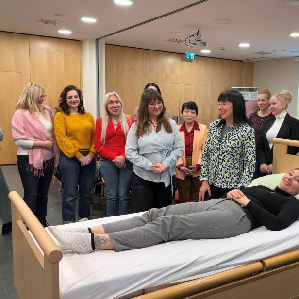 Mehrere Personen stehen um ein Bett herum