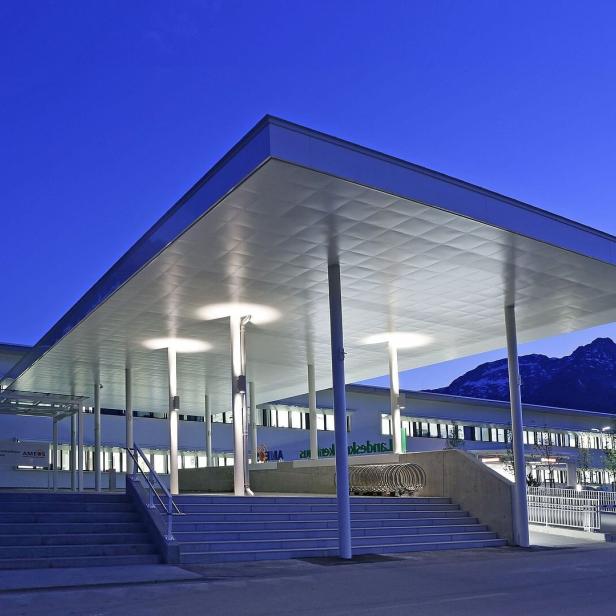 Das Landeskrankenhaus Bad Aussee mit großem Vordach und Bergkulisse im Abendlicht.