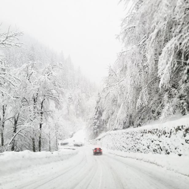 Ein Auto fährt auf der verschneiten Loiblpass-Bundesstraße.