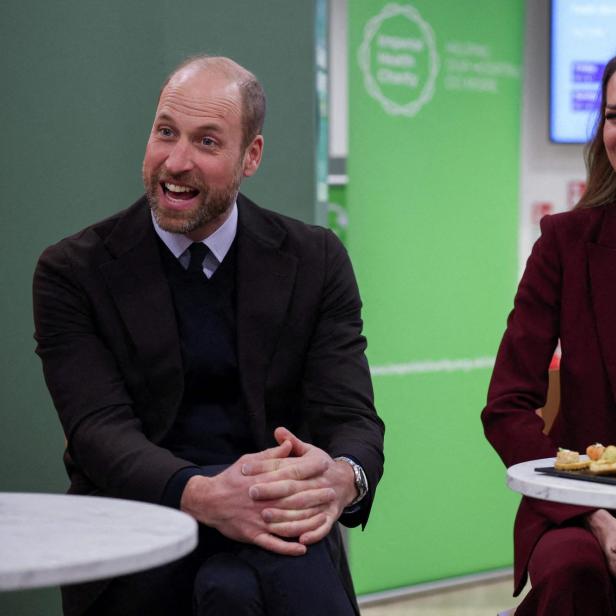 Prinz William und Prinzessin Kate lachen an einem Tisch mit Snacks.