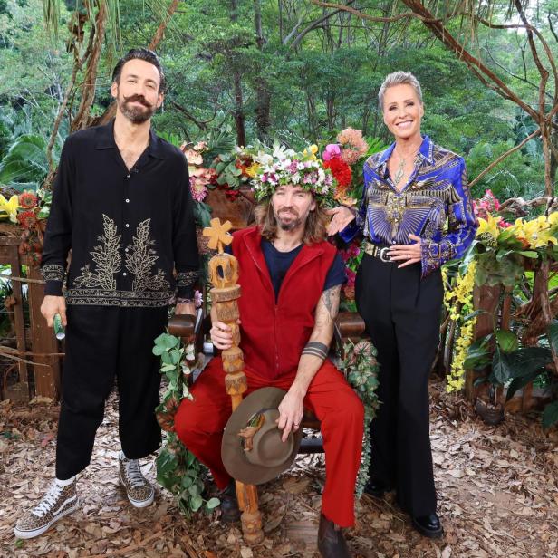 Gil Ofarim sitzt mit Dschungelkrone und Zepter zwischen den Moderatoren Sonja Zietlow und Jan Köppen im australischen Dschungelcamp.